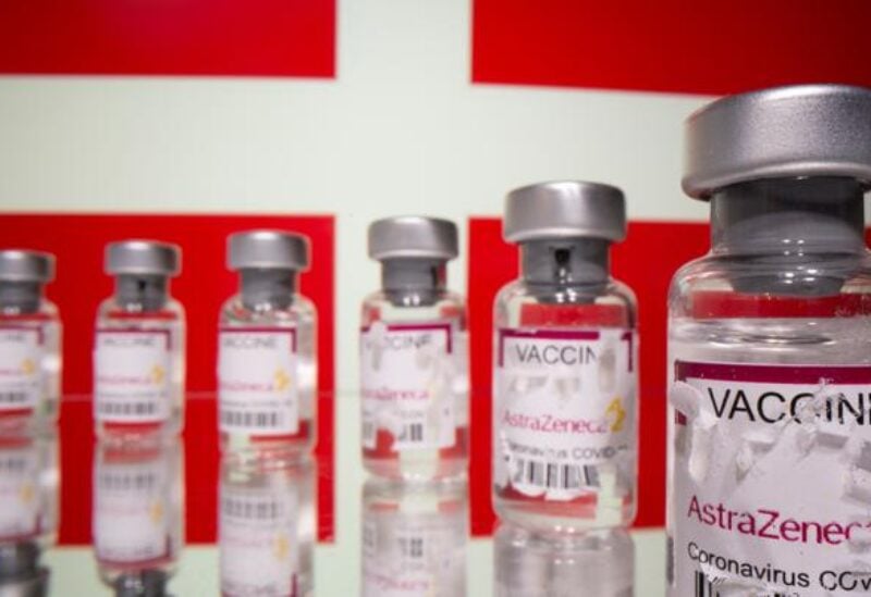 FILE PHOTO: Vials labelled with broken sticker "AstraZeneca COVID-19 Coronavirus Vaccine" are seen in front of a displayed Denmark flag in this illustration taken March 15, 2021.