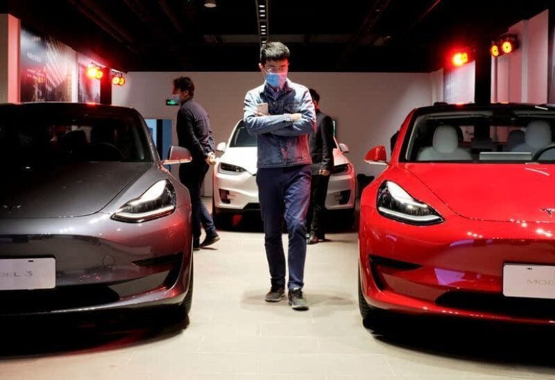 FILE PHOTO: A man wearing a face mask following the coronavirus disease (COVID-19) outbreak walks by Tesla Model 3 sedans and Tesla Model X sport utility vehicle at a new Tesla showroom in Shanghai, China May 8, 2020.