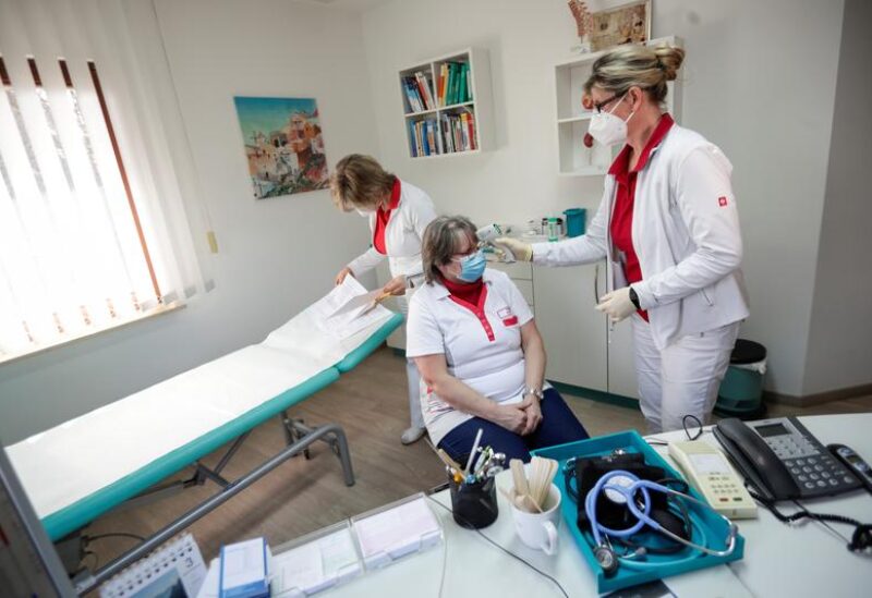 FILE PHOTO: A health worker checks the temperature of the nurse before vaccination, in the state of Brandenburg where the first coronavirus vaccinations are given in doctors' surgeries, in Senftenberg, Germany, March 3, 2021.