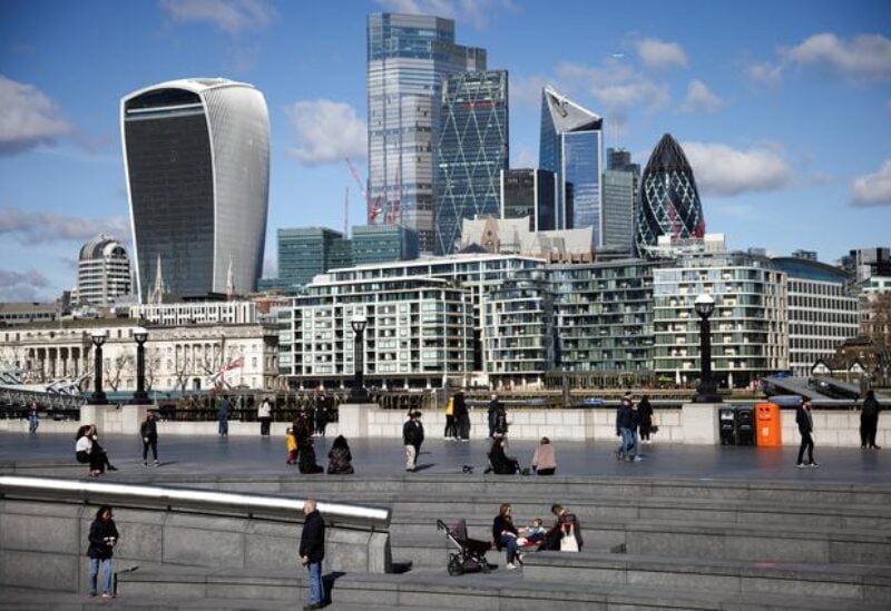 FILE PHOTO: The City of London financial district can be seen as people walk along the south side of the River Thames, amid the coronavirus disease (COVID-19) outbreak in London, Britain, March 19, 2021.
