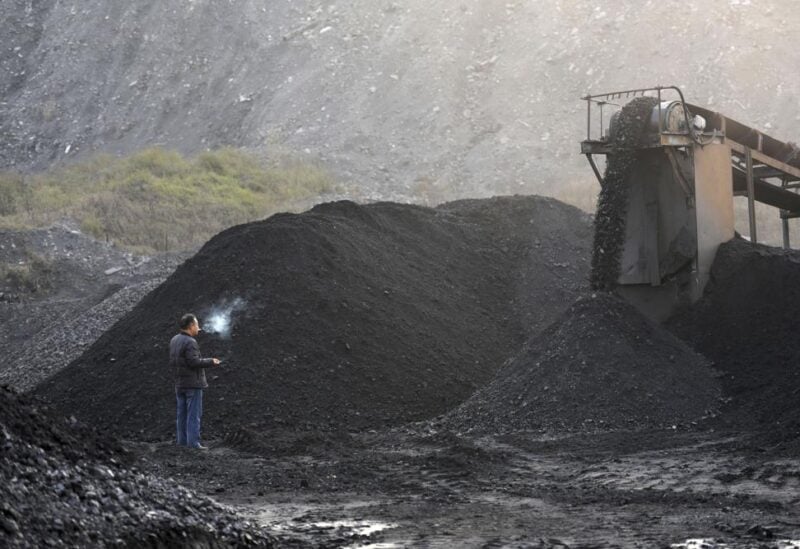 A worker stands near machinery moving coal in the yard of a coal mine in Huaibei in central China