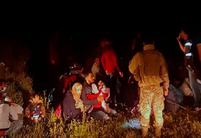 Lebanese troops stand next to Syrian migrants who tried to go by boat to the Mediterranean island of Cyprus