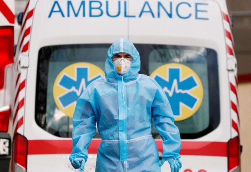 FILE PHOTO: A medical worker wearing protective gear stands next to an ambulance outside a hospital for patients infected with COVID-19 in Kyiv, Ukraine, November 24, 2020.