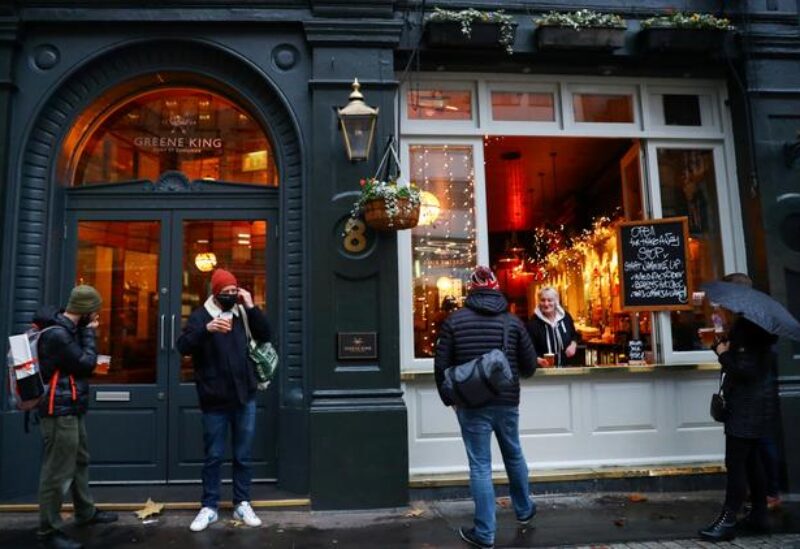 FILE PHOTO: People drink outside a pub that is open for takeaway drinks, amid the coronavirus disease (COVID-19) outbreak, in London, Britain December 16, 2020.