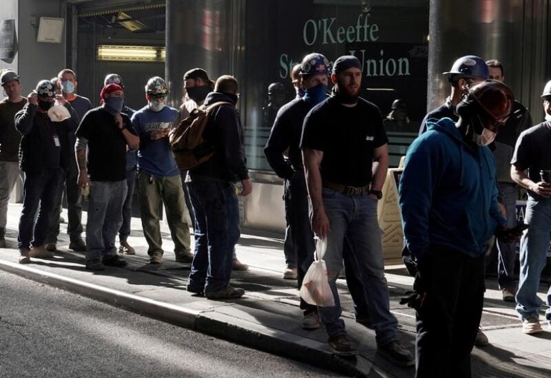 FILE PHOTO: Construction workers wait in line to do a temperature test to return to the job site after lunch, amid the coronavirus disease (COVID-19) outbreak, in the Manhattan borough of New York City, New York, U.S., November 10, 2020.
