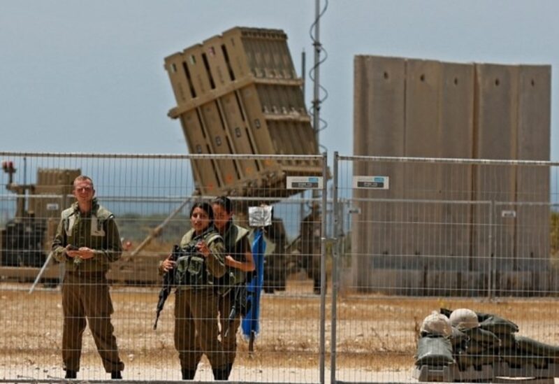 Israeli soldiers stand next to an Iron Dome aerial defence system set to intercept rockets launched from the Gaza Strip
