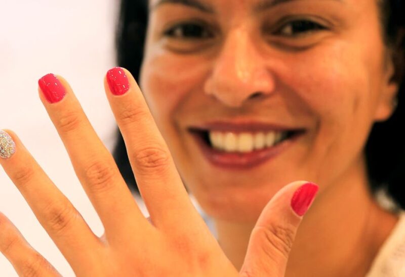 A customer looks on as she gets a microchip, containing personal data, attached to one of her nails at Lanour Beauty Lounge in Dubai. (File photo: Reuters)