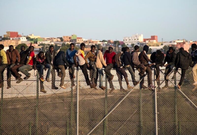 A file photo of would-be immigrants stand atop a boarder fence separating Morocco from the north African Spanish enclave of Melilla. (AFP)