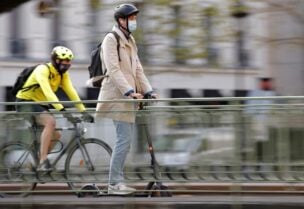 A man, wearing a protective face mask, rides a scooter past a biker on a bridge over the canal Saint-Martin in Paris amid the coronavirus (COVID-19) outbreak in France, April 22, 2021. (File photo: Reuters)