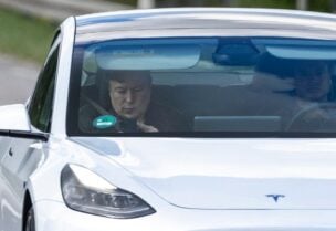 Tesla CEO Elon Musk (L) is seen as he uses his mobile device in the car arriving to the construction site for the new plant, the so-called "Giga Factory", of US electric carmaker Tesla, in Gruenheide near Berlin, northeastern Germany. (AFP)