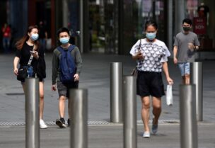 People wearing face masks cross a road amid the coronavirus disease (COVID-19) outbreak in Singapore May 20, 2021. REUTERS/Caroline Chia