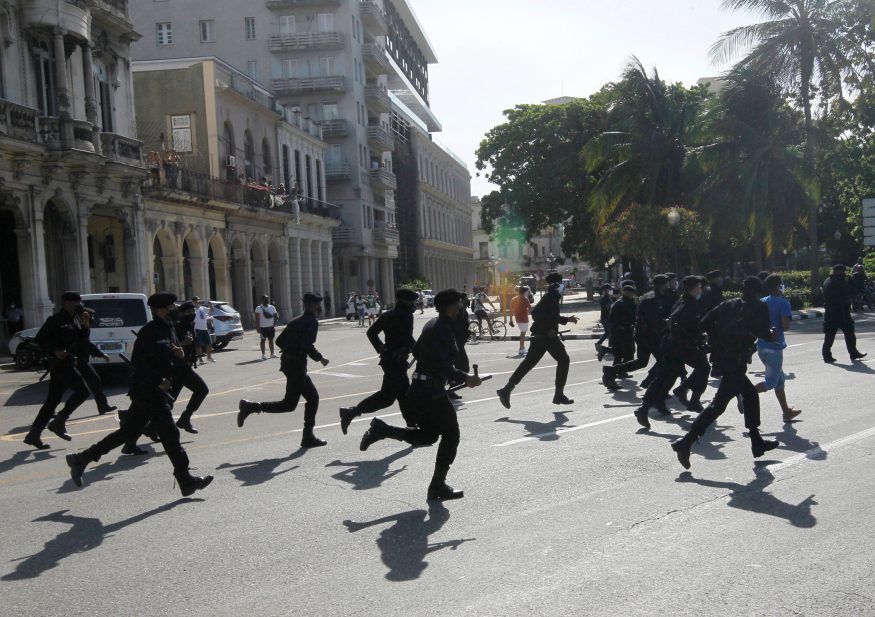 Police run during protests against and in support of the government, in Havana