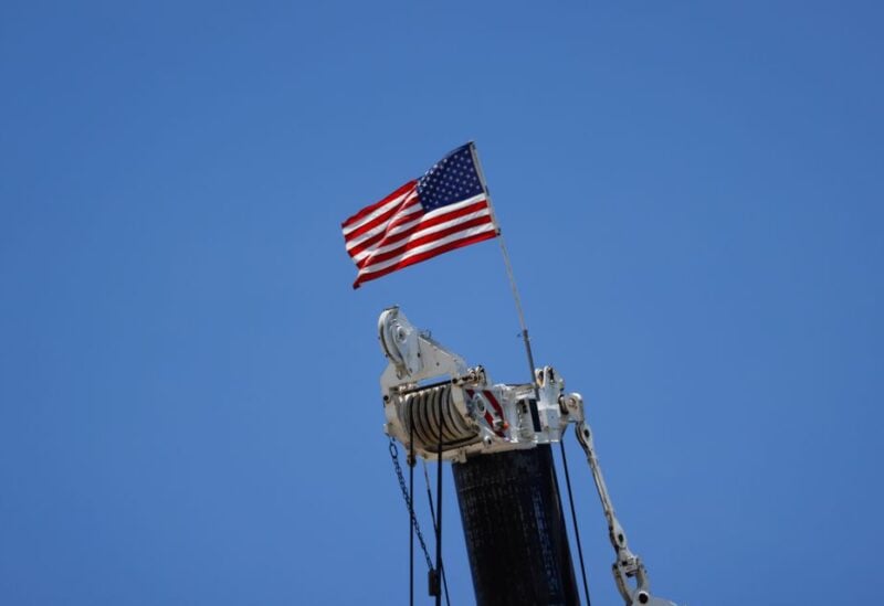 An American flag flutters atop a crane at the site of a partially collapsed residential building as the emergency crews continue the search and rescue operations for survivors, in Surfside, Florida, U.S. July 3, 2021. REUTERS/Marco Bello