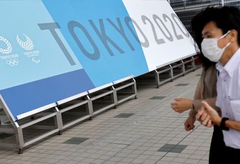 People walk past a sign for the 2020 Tokyo Olympic Games that have been postponed to 2021 due to the coronavirus disease (COVID-19) pandemic, at the IBC/MPC media center at Tokyo Big Sight exhibition center in Tokyo, Japan June 30, 2021. REUTERS/Fabrizio Bensch