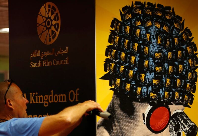 A worker installs a poster of the Saudi Film Council inside the Film Market business area in 2018. (File photo: Reuters)