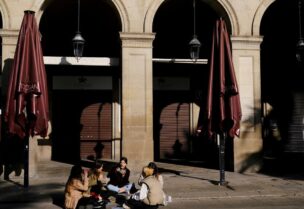 Women eat while sitting in front of a closed restaurant at the empty Plaza Reial (Reial square), after Catalonia's government imposed new restrictions in an effort to control the spread of the coronavirus disease (COVID-19), in Barcelona, Spain January 26, 2021. (Reuters)