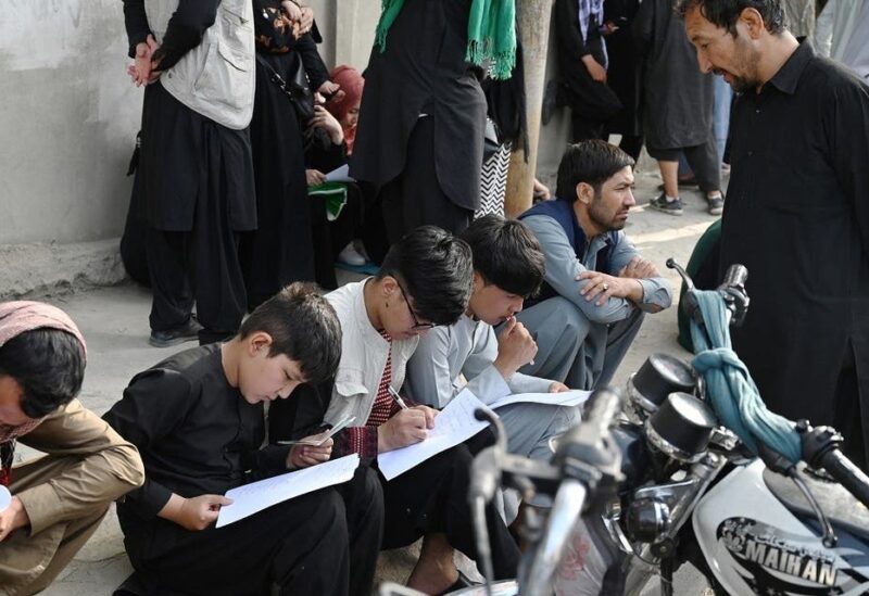 Afghan people fill up their details on a sheet of paper to register their name in order to leaves the country in front of the British and Canadian embassy in Kabul on August 19, 2021 after Taliban's military takeover of Afghanistan. (AFP)