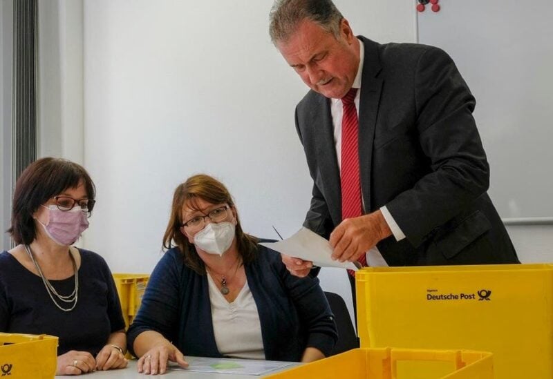 The chairman of the German train drivers' union GDL Claus Weselsky looks at an envelope of ballots before GDL members count the votes on possible strikes at Deutsche Bahn, on August 9, 2021 at the GDL headquarters in Frankfurt, western Germany. (AFP)