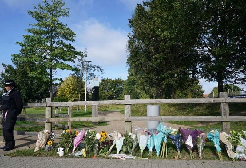 A police officer stands by floral tributes at Cator Park in Kidbrooke, near to the area where the body of Sabina Nessa was found, in London, on Sept. 23, 2021. (AP)