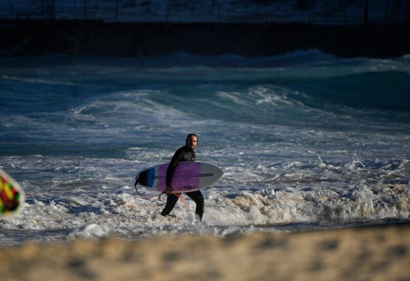 A surfer walks at Bondi Beach in Sydney on August 18, 2021. (AFP)