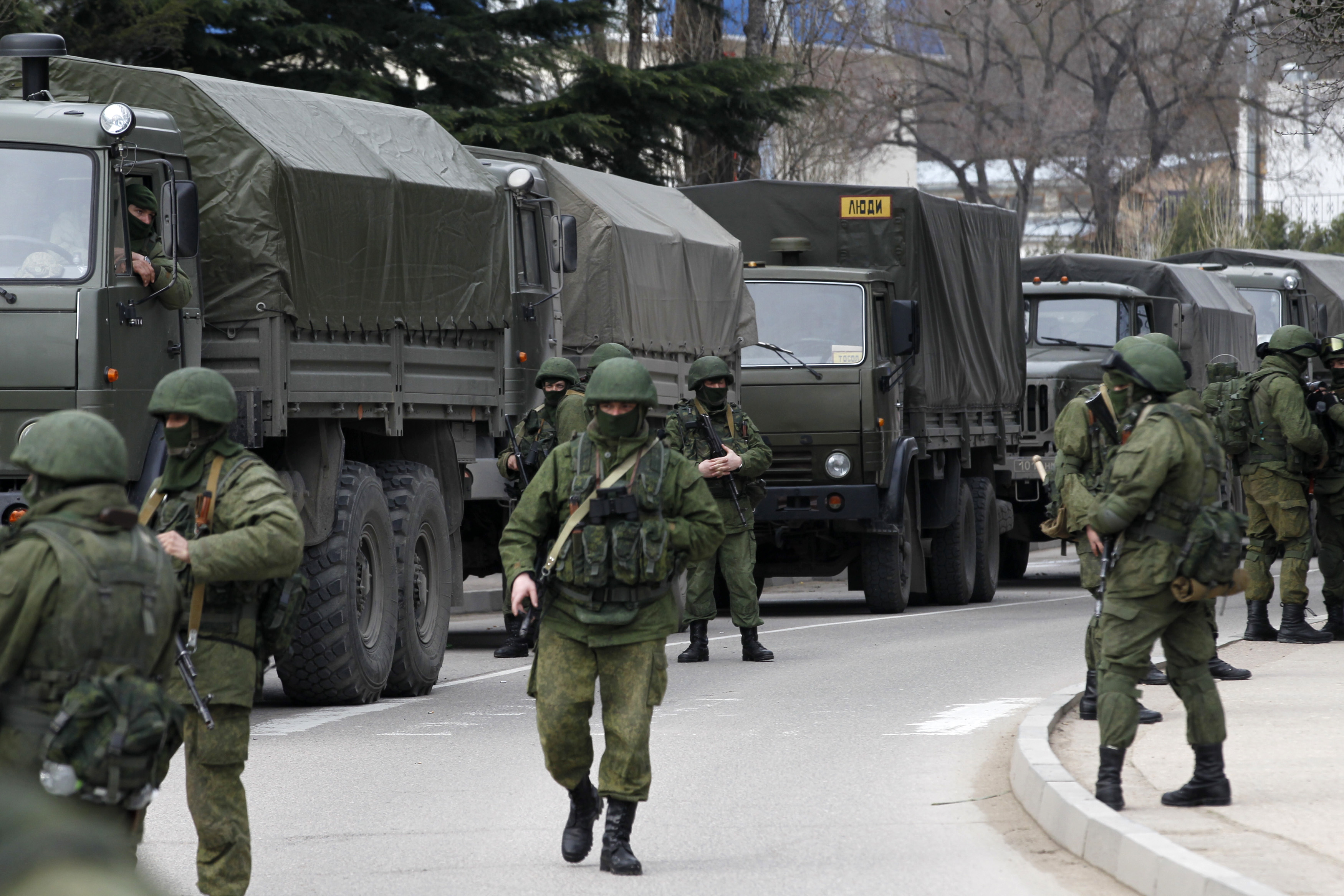 Armed servicemen wait near Russian army vehicles outside a Ukrainian border guard post in the Crimean town of Balaclava