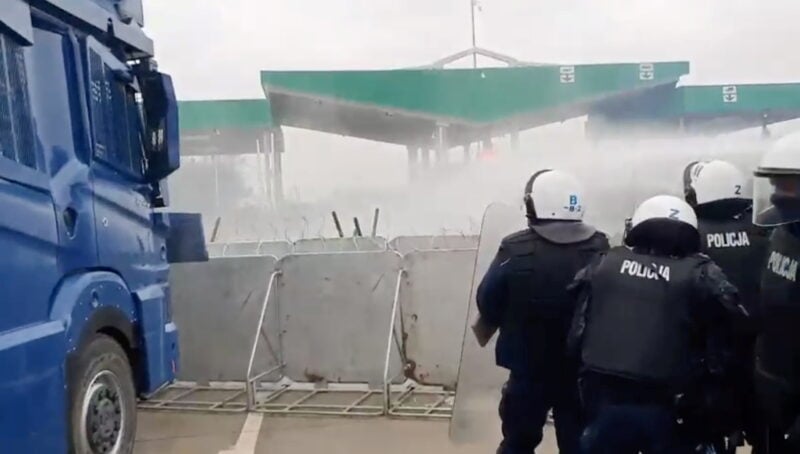 A still image, taken from a handout video released by the Polish Defence Ministry, shows Polish law enforcement officers, who stand guard and use a water cannon on migrants at Kuznica - Bruzgi checkpoint on the Polish-Belarusian border, Poland, November 16, 2021. MON/Handout via REUTERS .