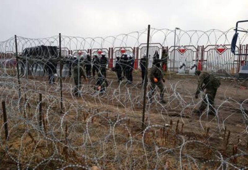 A view from a migrants' camp shows Polish law enforcement officers, who stand guard behind a fence on the Belarusian-Polish border in the Grodno region, Belarus November 17, 2021. Maxim Guchek/BelTA/Handout via REUTERS