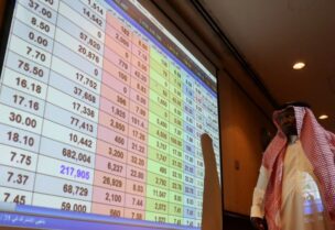 A Saudi man keeping an eye on a screen displaying stock market figures