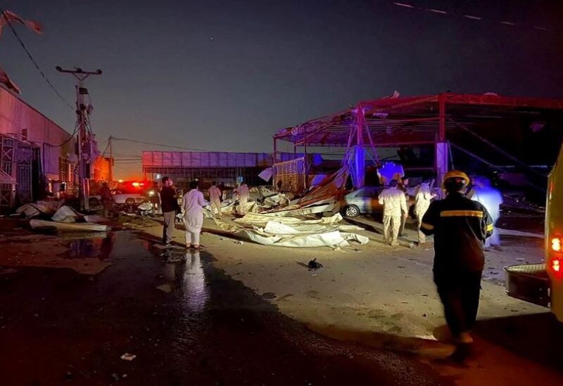 Residents and civil defence officials stand near cars and buildings damaged by shrapnel from the intercepted ballistic missile that landed in an industrial area, in south of Dhahran, Saudi Arabia,