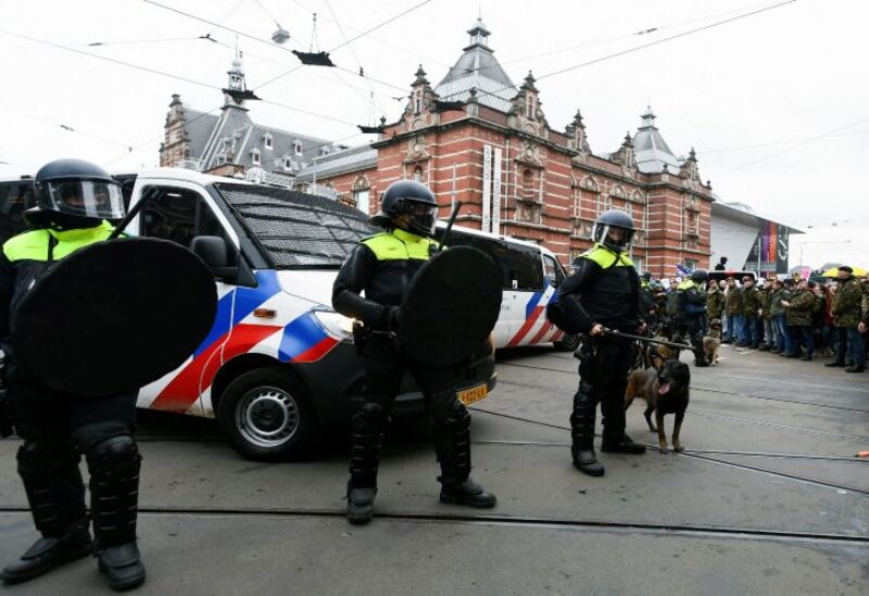 Police officers stand guard as opponents of restrictions imposed in the Netherlands