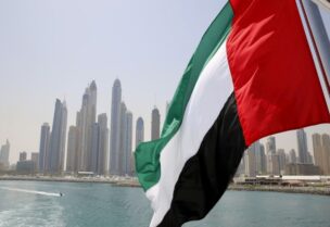 UAE flag flies over a boat at Dubai Marina, Dubai, United Arab Emirates