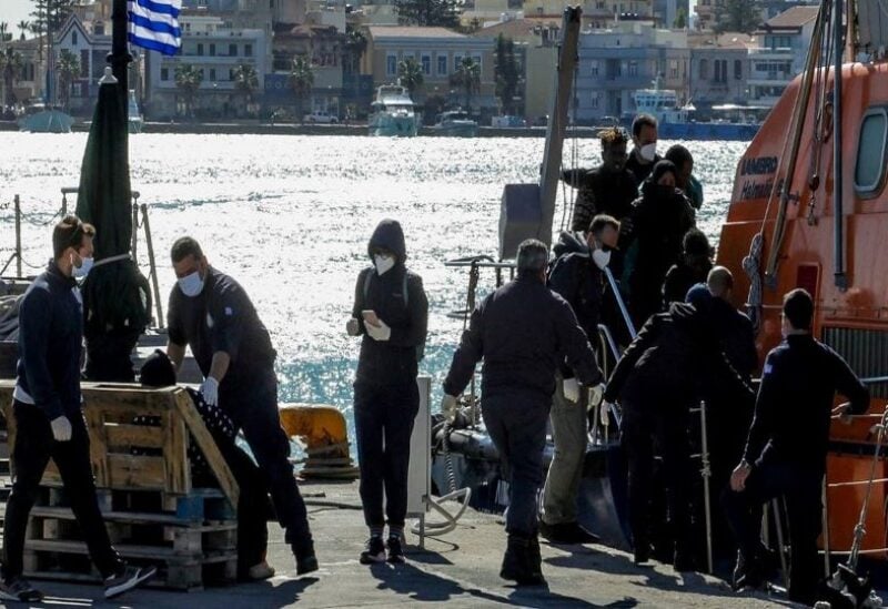 A migrant is helped by a Hellenic Coast Guard officer as other migrants disembark a Hellenic Coast Guard vessel after being rescued at open sea, on the island of Chios, Greece