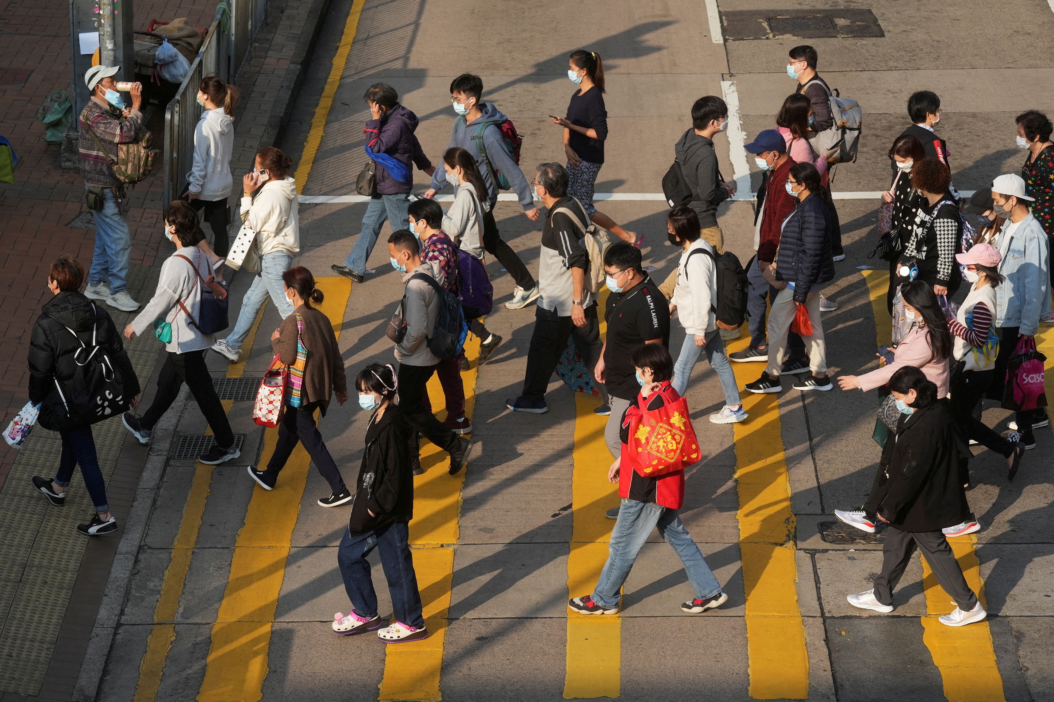 FILE PHOTO: People wearing face masks cross a street following the coronavirus disease (COVID-19) outbreak, in Hong Kong, China February 15, 2022. REUTERS/Lam Yik