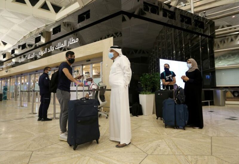 A Saudi man wearing a face mask gets his passport from a Saudi Immigration officer, at the King Khalid International Airport,