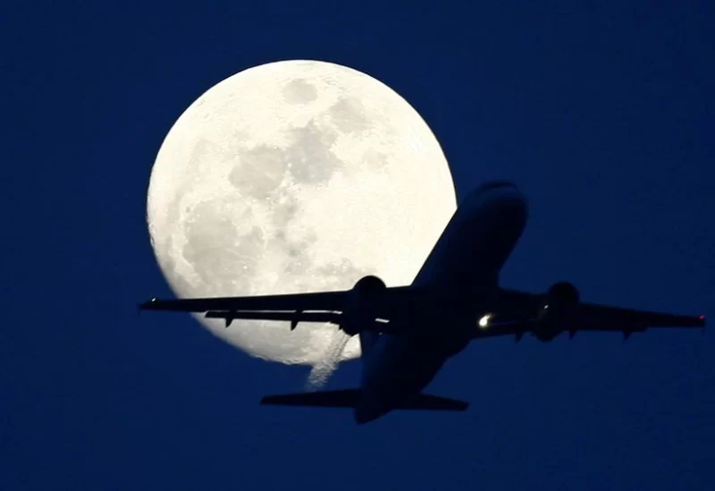 A passenger aircraft is silhouetted against the rising moon in New Delhi May 7, 2009.