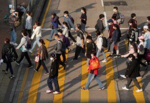 People wearing face masks cross a street following the coronavirus disease (COVID-19) outbreak, in Hong Kong, China February 15, 2022. REUTERS/Lam Yik