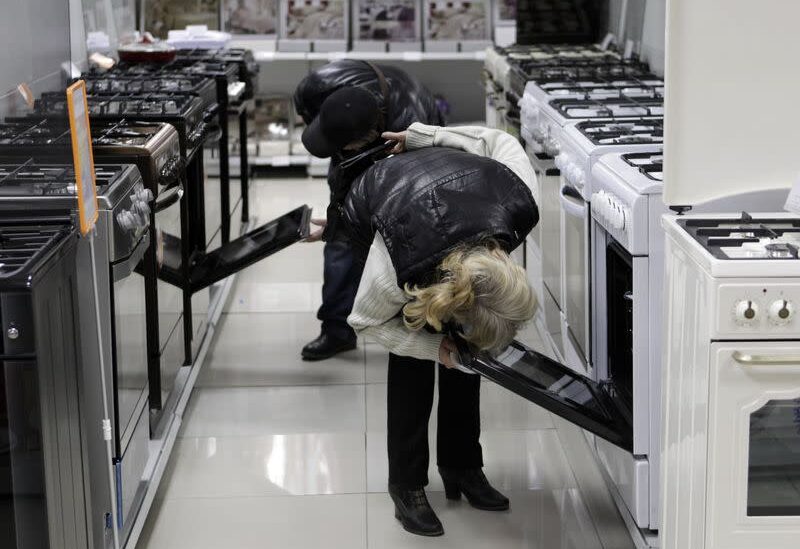 Customers inspect kitchen stoves at an electronic store