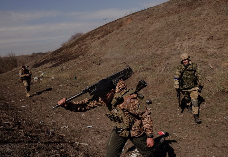 A Ukrainian soldier carries Russian weapons captured during a battle between Ukrainian and Russian forces outside Kharkiv, as Russia's attack on Ukraine continues, Ukraine, March 29, 2022. REUTERS/Thomas Peter