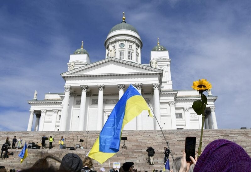 People hold a Ukrainian flag and a sunflower as they take part in an ecumenical prayer moment in support of Ukraine amid Russia's invasion and for peace in the world, on Easter Monday at the Senate Square by the stairs of the Helsinki Cathedral in Helsinki, Finland, April 18, 2022. Emmi Korhonen/Lehtikuva/via REUTERS