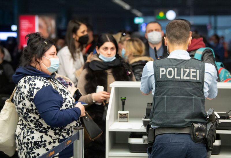 A German police officer checks the documents of Ukrainian refugees who arrived in Germany with a first refugee plane from Moldova, after fleeing from Russia's invasion of Ukraine, at the international airport of Frankfurt, Germany, March 25, 2022. Boris Roessler/Pool via REUTERS