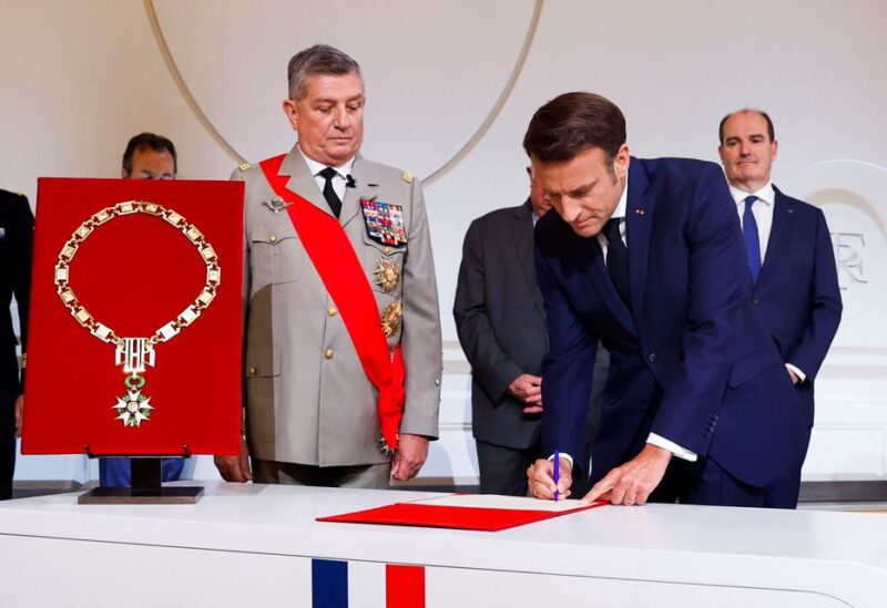 France's Military Chief of Staff to the presidency Benoit Puga stands next to French President Emmanuel Macron signing a document as he is sworn-in for a second term as president after his re-election, during a ceremony at the Elysee Palace in Paris, France, May 7, 2022. REUTERS/Gonzalo Fuentes/Pool