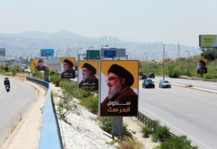 Vehicles drive past billboards depicting Lebanon's Hezbollah leader Sayyed Hassan Nasrallah