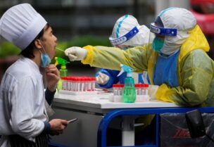 A medical worker in a protective suit collects a swab sample from a chef for nucleic acid testing, during lockdown, amid the coronavirus disease (COVID-19) pandemic, in Shanghai, China, May 13, 2022. REUTERS/Aly Song
