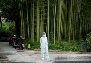A woman in a protective suit stands on a street during lockdown, amid the coronavirus disease (COVID-19) pandemic, in Shanghai, China, May 26, 2022. REUTERS/Aly Song