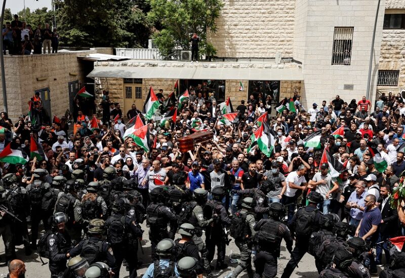 Family and friends carry the coffin of Al Jazeera reporter Shireen Abu Akleh, who was killed during an Israeli raid in Jenin in the occupied West Bank, as Israeli security forces stand guard, during her funeral in Jerusalem, May 13, 2022. REUTERS/Ammar Awad