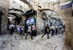 Jewish men carry Israeli national flags as they walk in an alley, inside Jerusalem's Old city May 29, 2022. REUTERS/Ammar Awad