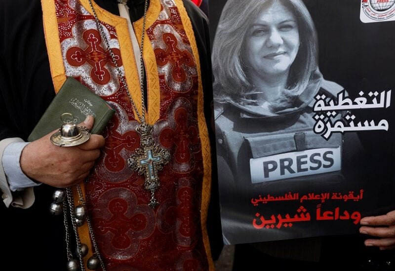 A priest holds a poster depicting Al Jazeera reporter Shireen Abu Akleh who was killed in an Israeli raid, in Ramallah, in the Israeli-occupied West Bank May 11, 2022. REUTERS/Mohamad Torokman