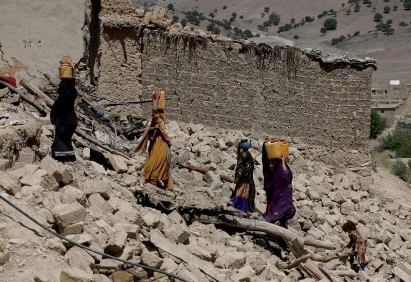 Afghan women carry water containers through the debris of damaged houses after the recent earthquake in Wor Kali village in the Barmal district of Paktika province, Afghanistan, June 25, 2022. REUTERS/Ali Khara