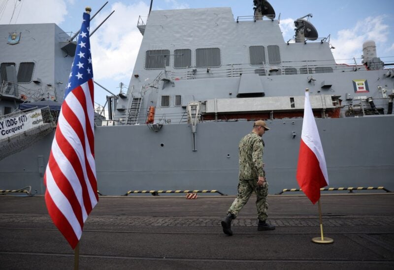 A U.S. Marine walks between U.S. and Polish flag before conference in front of U.S. Navy's warship USS Gravely which docked in the Baltic sea port city of Gdynia in what was described by officials as a show of support for the country as war rages in neighboring Ukraine, Poland June 7, 2022. REUTERS/Kacper Pempel/Files