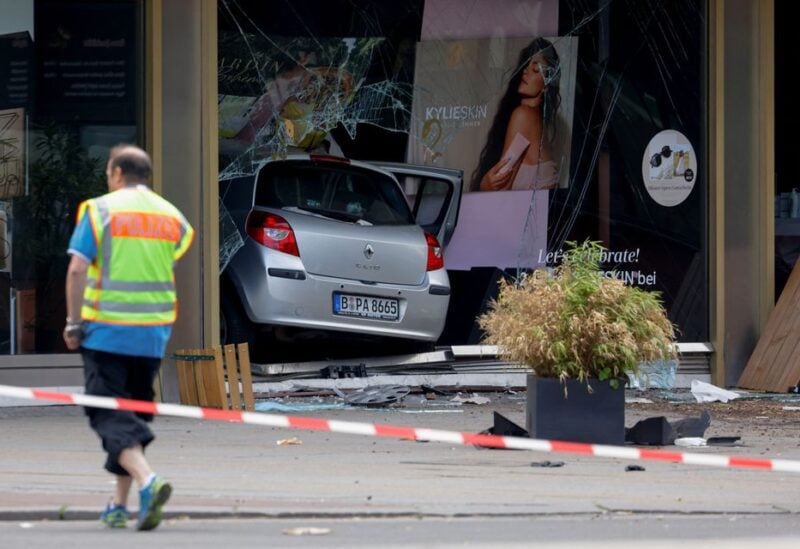 A man wearing a police vest walks near a car that crashed into a group of people and ended up in a storefront near Breitscheidplatz in Berlin, Germany, June 8, 2022. REUTERS/Michele Tantussi